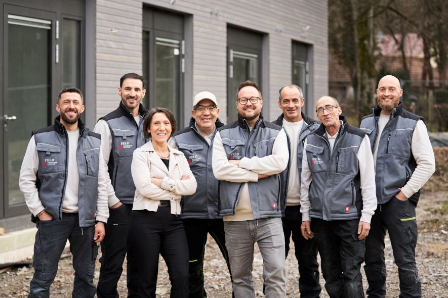 Mitarbeiter von Feld Fußbodensysteme sind in Arbeitskleidung auf einem Gruppenfoto zu sehen.