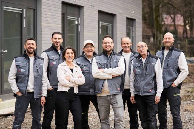 Mitarbeiter von Feld Fußbodensysteme sind in Arbeitskleidung auf einem Gruppenfoto zu sehen.
